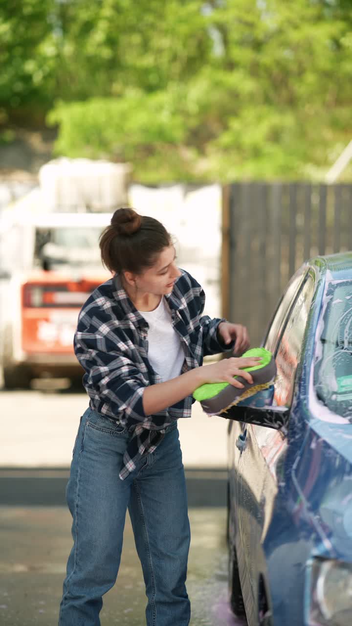 una mujer lavando un coche.