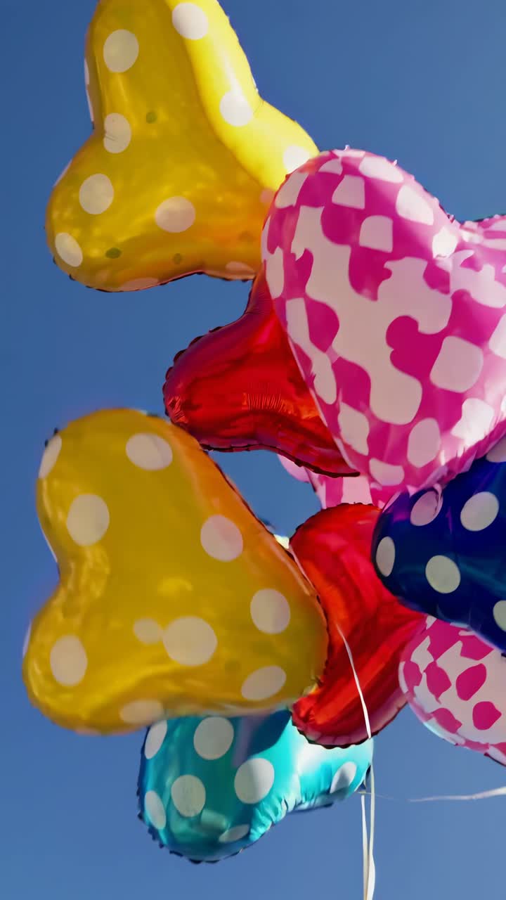 Palloncini a forma di cuore a pois che fluttuano in un cielo azzurro brillante.
