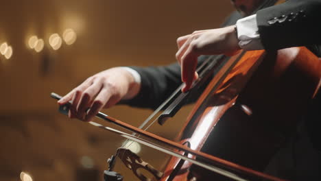 talented man is playing cello on scene of old opera house closeup of hands of cellist