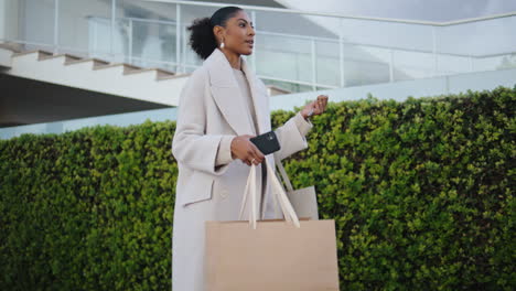 elegant woman walking street with shopping bags. smiling black hair girl commute