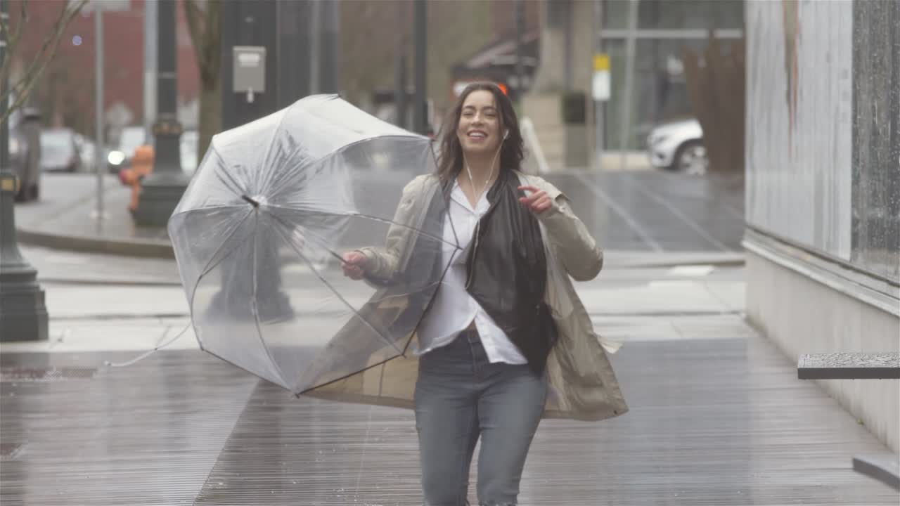 joven hermosa mujer latina bailando con un paraguas en la ciudad mientras escucha música