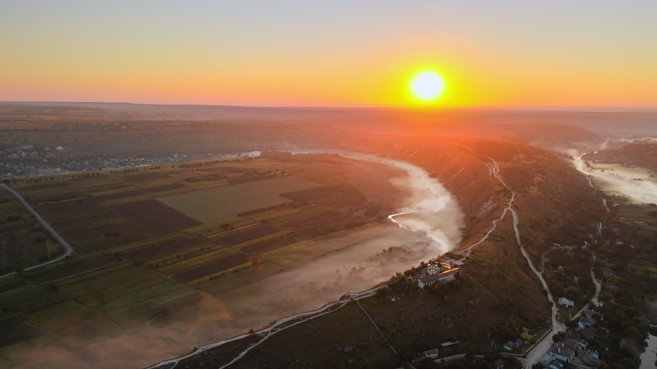 Aerial drone view of the Old Orhei at sunset. Valley with river and fog, village, monastery located on a hill in Moldova