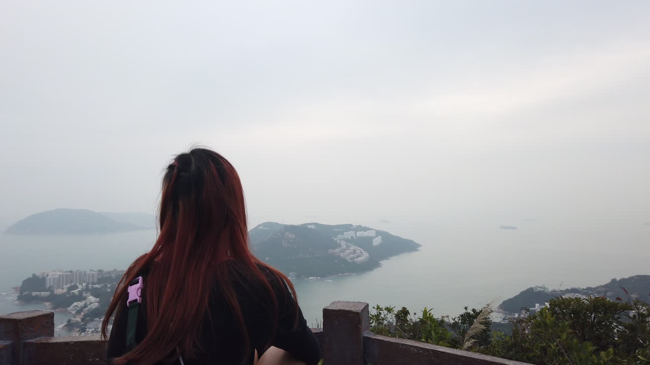 Orbit shot of Red haired girl looking at Stanley Peninsula at the beginning of the Wilson Trail, Hong Kong