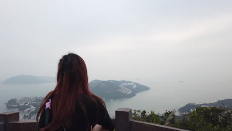 Orbit-shot-of-Red-haired-girl-looking-at-Stanley-Peninsula-at-the-beginning-of-the-Wilson-Trail,-Hong-Kong