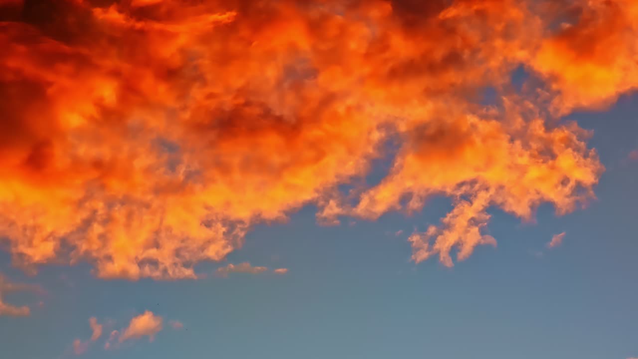 Fiery sunset clouds illuminate summer sky in dramatic color patterns