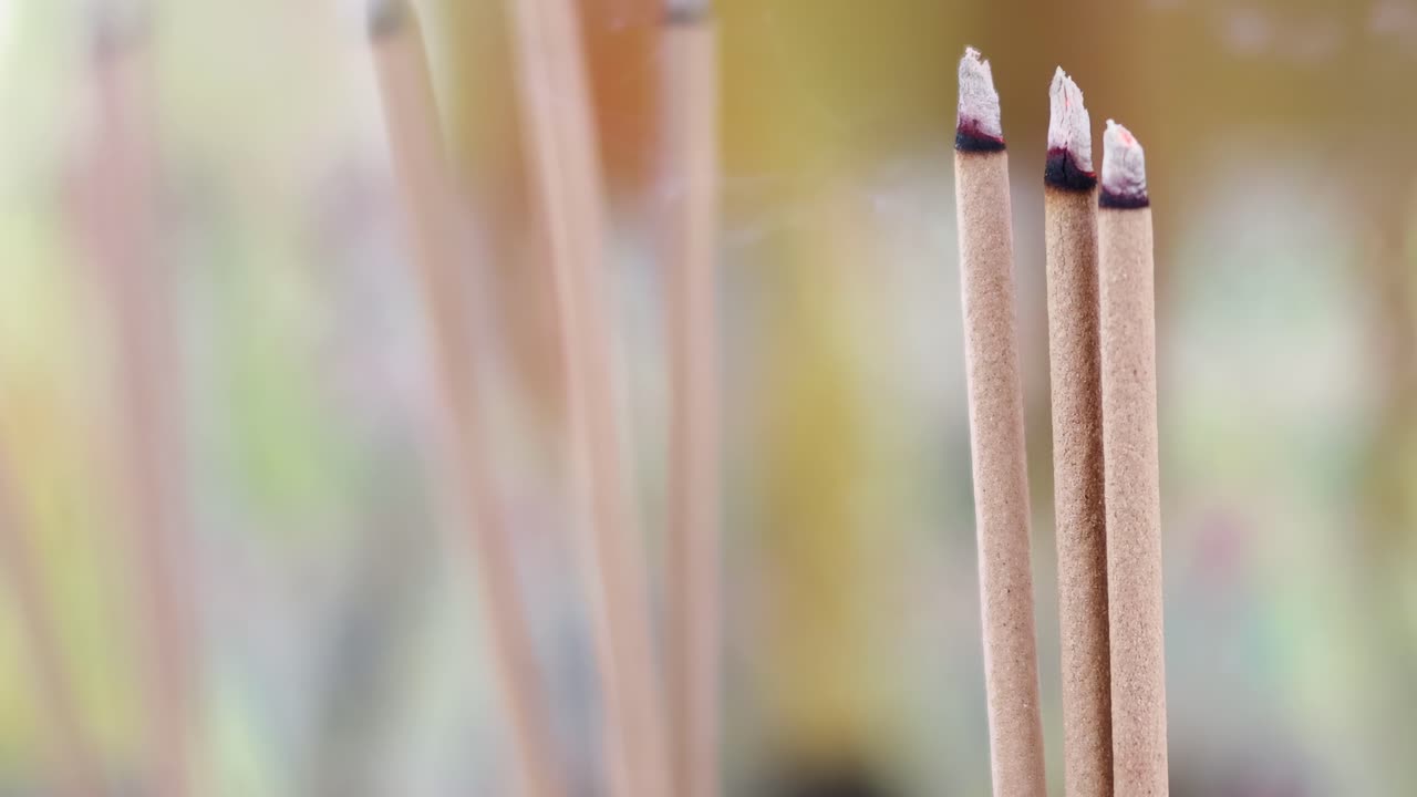 Detailed view of incense sticks with gentle smoke trails against a blurred background.
