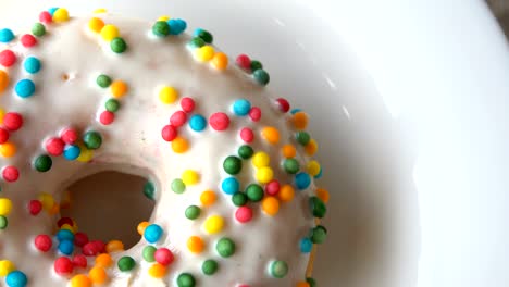 delicious sweet donut with white icing rotating on a plate. rustic wooden table. looped