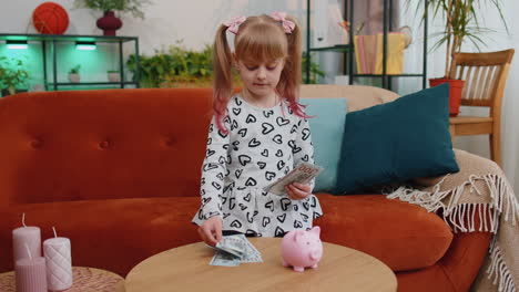 niña pequeña contando dinero billetes de dólar para necesidades futuras en el escritorio de casa con la alcancía