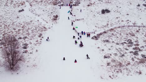 Antena-De-Un-Niño-Bajando-En-Trineo-Por-Una-Colina-Nevada-A-Gran-Velocidad