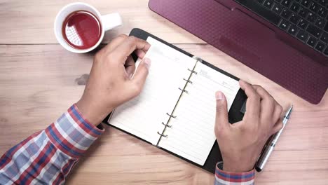 persona que trabaja en un escritorio con un cuaderno, una taza de café y una computadora portátil