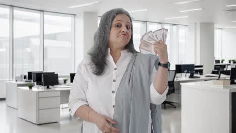 una mujer de negocios india segura de sí misma usando el dinero como ventilador.