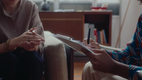 therapist writing down notes during conversation with patient