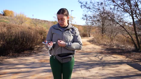 Woman takes earphones out of her fanny pack, connects them to her smartphone and starts running