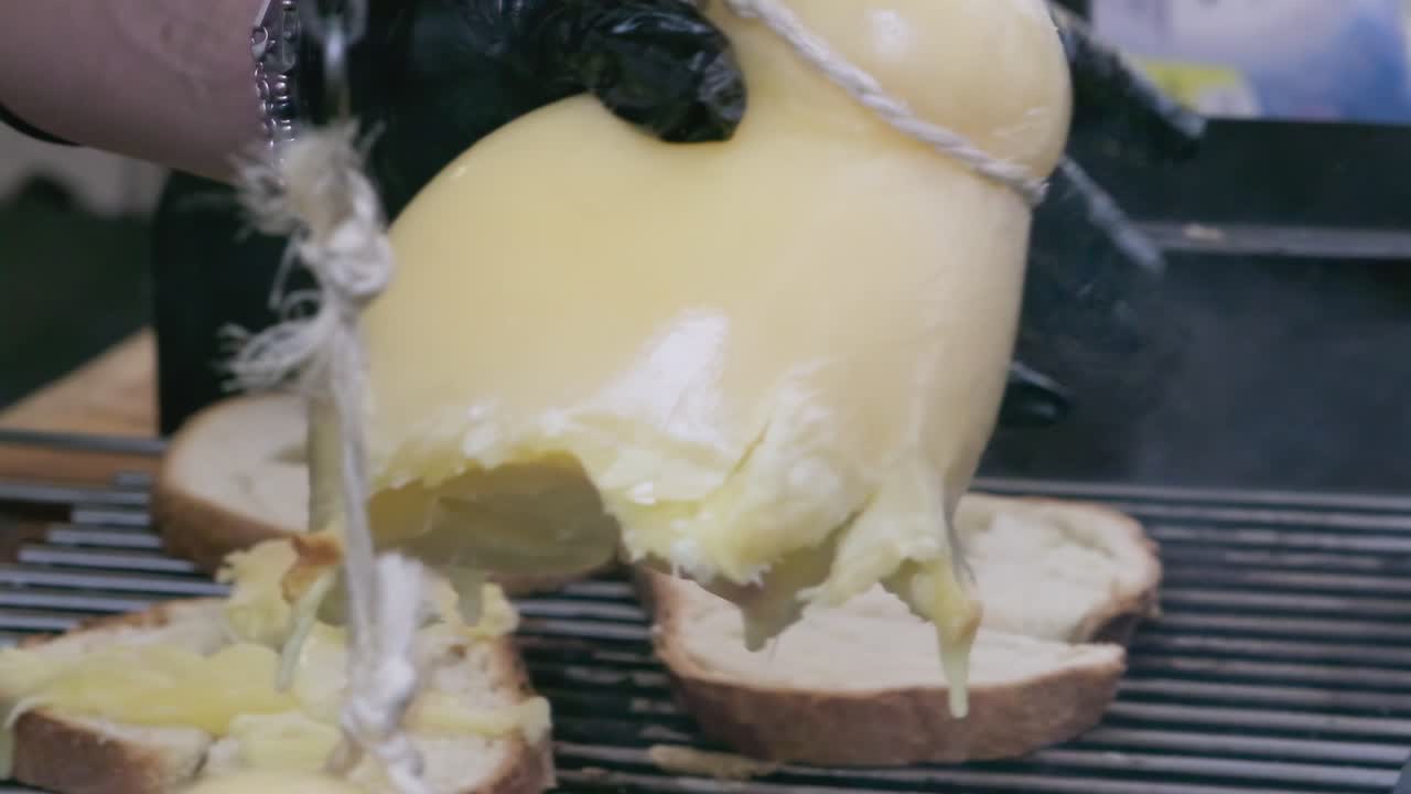 Chef hands picking melting traditional caciocavallo cheese in slow motion, ready to be spread on bread slices. Artisanal Italian dairy showcases rich cultural heritage and gourmet craftsmanship