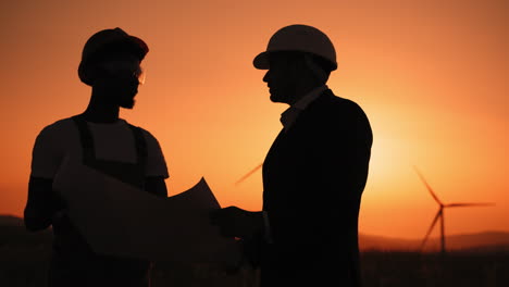 engineers discussing wind farm plans at sunset