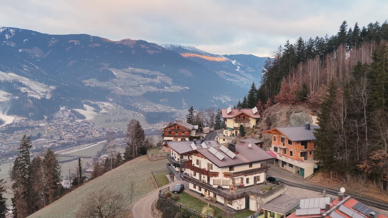 Riprese aeree della valle di Kaltenbach all'alba, colori caldi che si diffondono su terreni aperti e pendii. Una leggera nebbia si muove tra i campi mentre appaiono edifici e sentieri. L'ambientazione sottolinea la pace