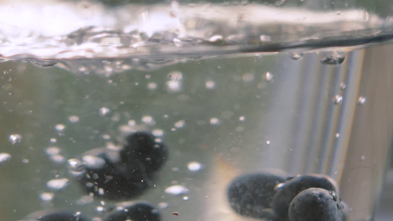 Close Up of Blueberries Falling into Water Bowl in Slow Motion. Ripe Fruit High in Magnesium and Fibre. Healthy Eating Food Footage