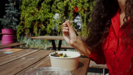 mujer comiendo comida al aire libre con palillos