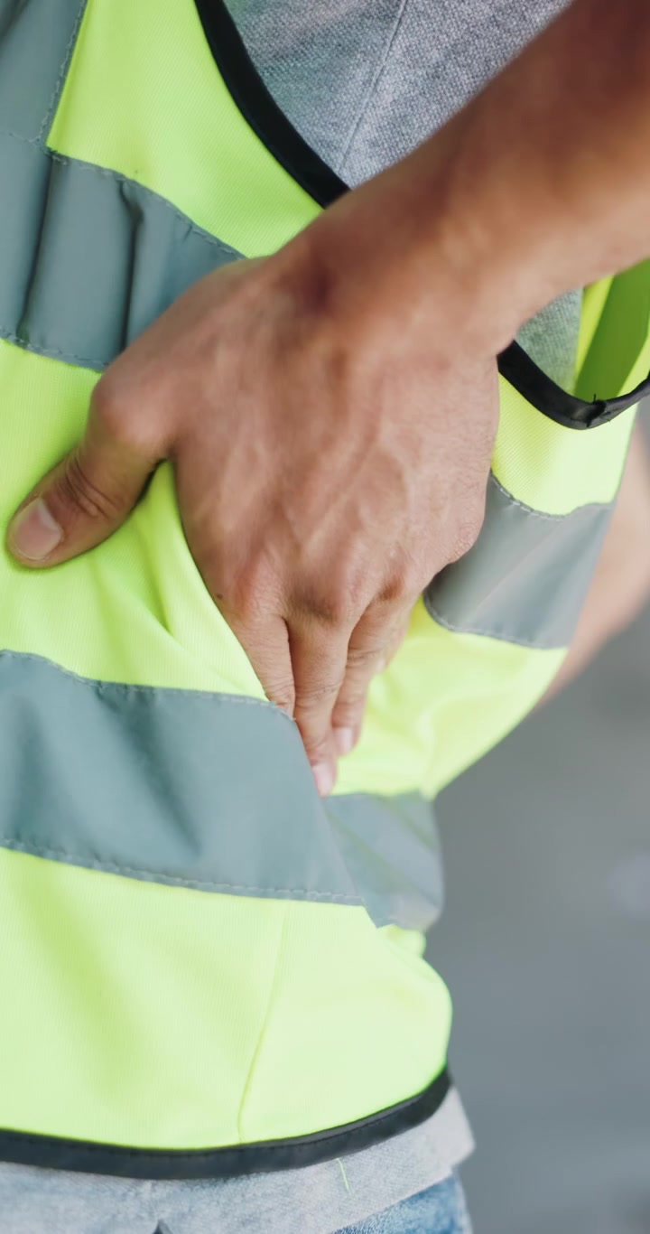 Trabajador de la construcción sosteniéndose la parte baja de la espalda por dolor
