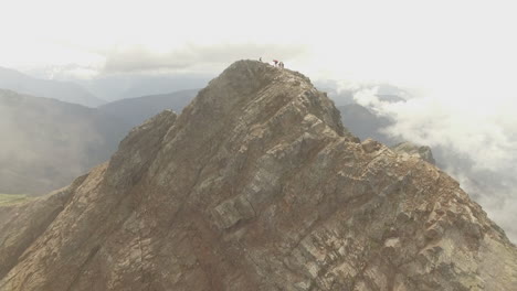 hikers are silhouetted atop a narrow mountain ridge