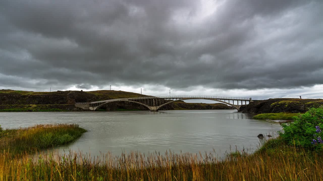 espesas nubes grises sobre el famoso puente hvita, un puente de carretera de un solo carril que atraviesa el río hvita en islandia, durante un día nublado - lapso de tiempo