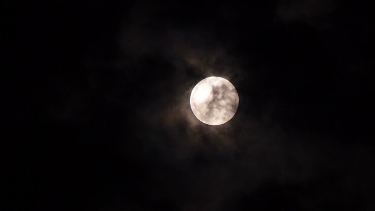 close-up lua cheia em uma noite escura com nuvens se movendo sobre ele. movimento 4k b-roll imagens