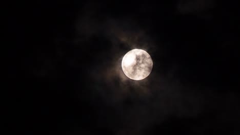 closeup full moon on a dark night with clouds moving over it. motion 4k b-roll footage