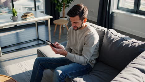man relaxing on a couch and using his smartphone in a modern living room