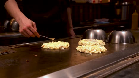 4k japanese chef prepares 3 japanese pancakes on a hot plate