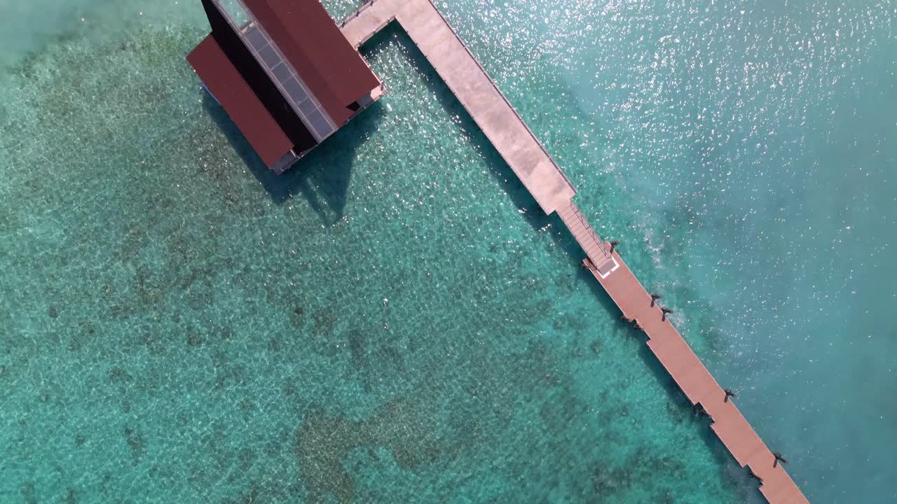 Sorvolo aereo di splendide acque azzurre, onde dell'oceano che si infrangono su spiaggia selvaggia e passerella