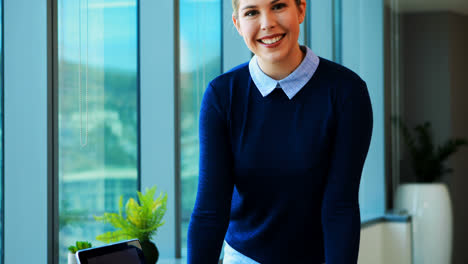 Female-executive-standing-at-her-desk-in-office