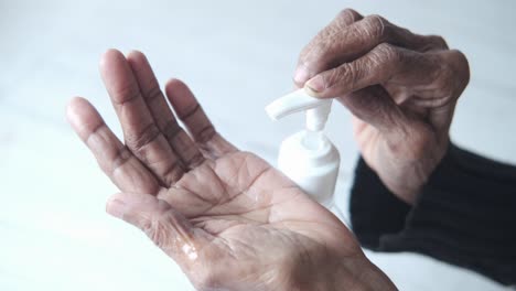 persona de edad avanzada que aplica desinfectante para las manos