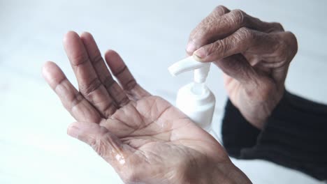 elderly person applying hand sanitizer