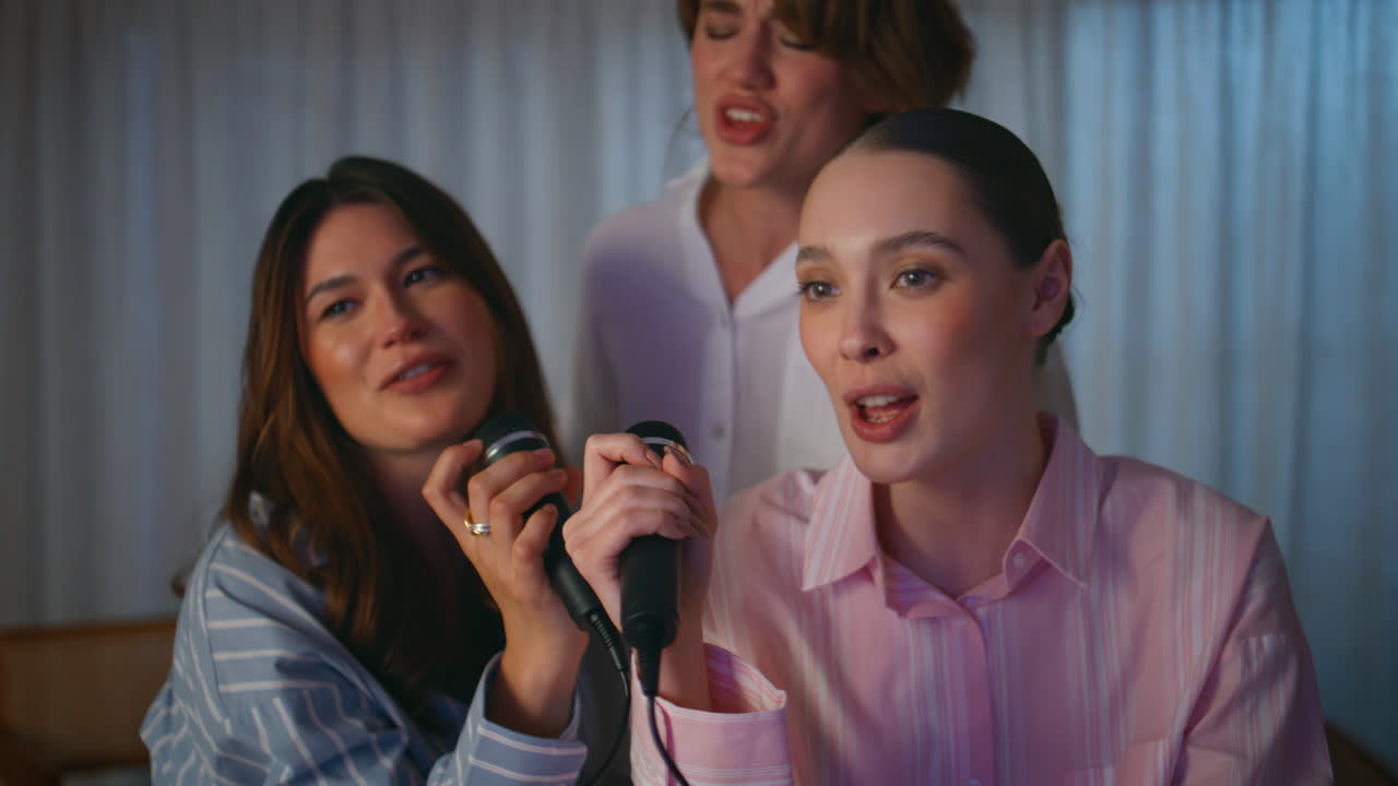 Pajamas friends singing karaoke at domestic hen party home closeup. Three women
