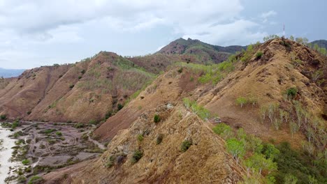 Luftdrohne-Steigt-über-Der-Braunen-Hügellandschaft-Der-Trockenzeit-Mit-Einem-Telekommunikationsturm-An-Der-Spitze-Auf-Der-Tropischen-Insel-Dili,-Timor-Leste,-Südostasien