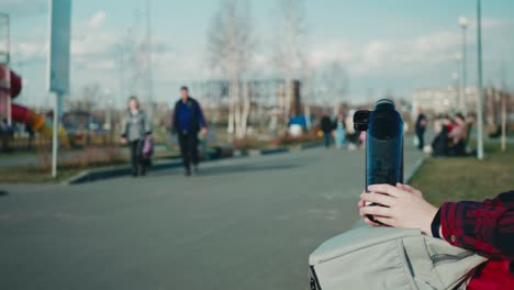 hands hold plastic reusable water bottle against blurry background of outdoors