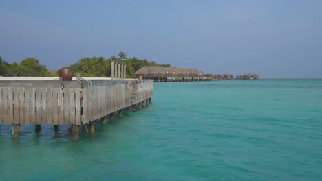 dock of maldives resort con bungalows sobre el agua en segundo plano.