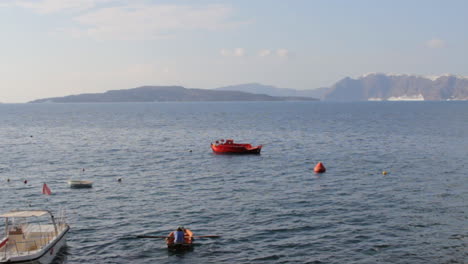 a man is paddling in the aegean sea, inside the santorini caldera