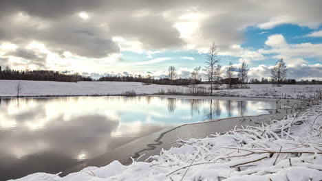 Zeitraffer-Von-Wolken,-Die-über-Einen-Spiegelnden,-Von-Schnee-Umgebenen-See-Ziehen