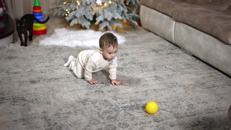 baby crawling and playing with balls near christmas tree