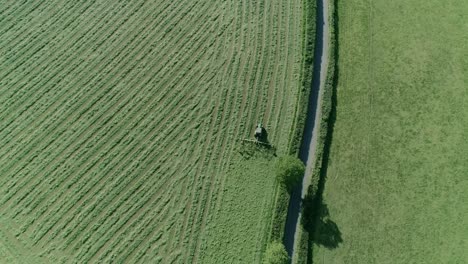 aerial of a tractor working the field alongside a rural english country road