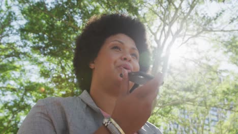 happy plus size biracial woman talking on smartphone in park