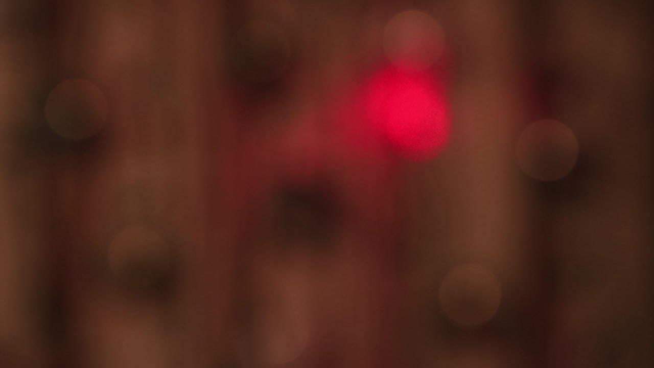 delicadas luces blancas festivas se balancean en la oscuridad y un lento rayo rojo.