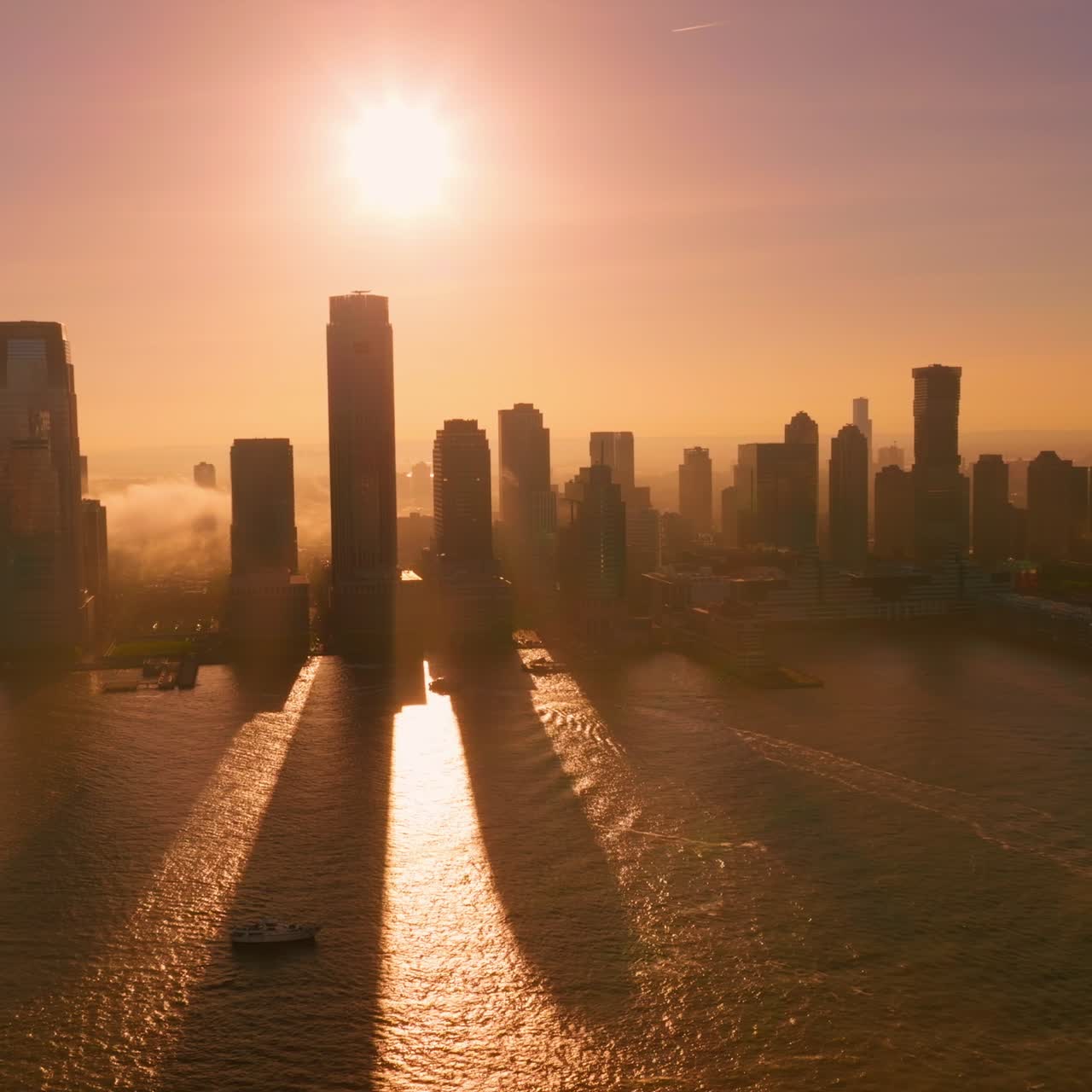 Ilha de Manhattan ao pôr do sol e com névoa densa. Arranha-céus projetando longas sombras sobre a água. Lindo plano de fundo com céu rosa.