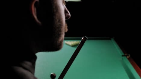 handsome bearded man rubbing cue with chalk at bar.