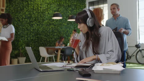 Joven-Mujer-De-Negocios-Asiática-Escribiendo-Notas-Disfrutando-Del-Estudio-Escuchando-Música-Usando-Auriculares-Estudiante-Bebiendo-Jugo-En-Diversos-Lugares-De-Trabajo-De-Oficina