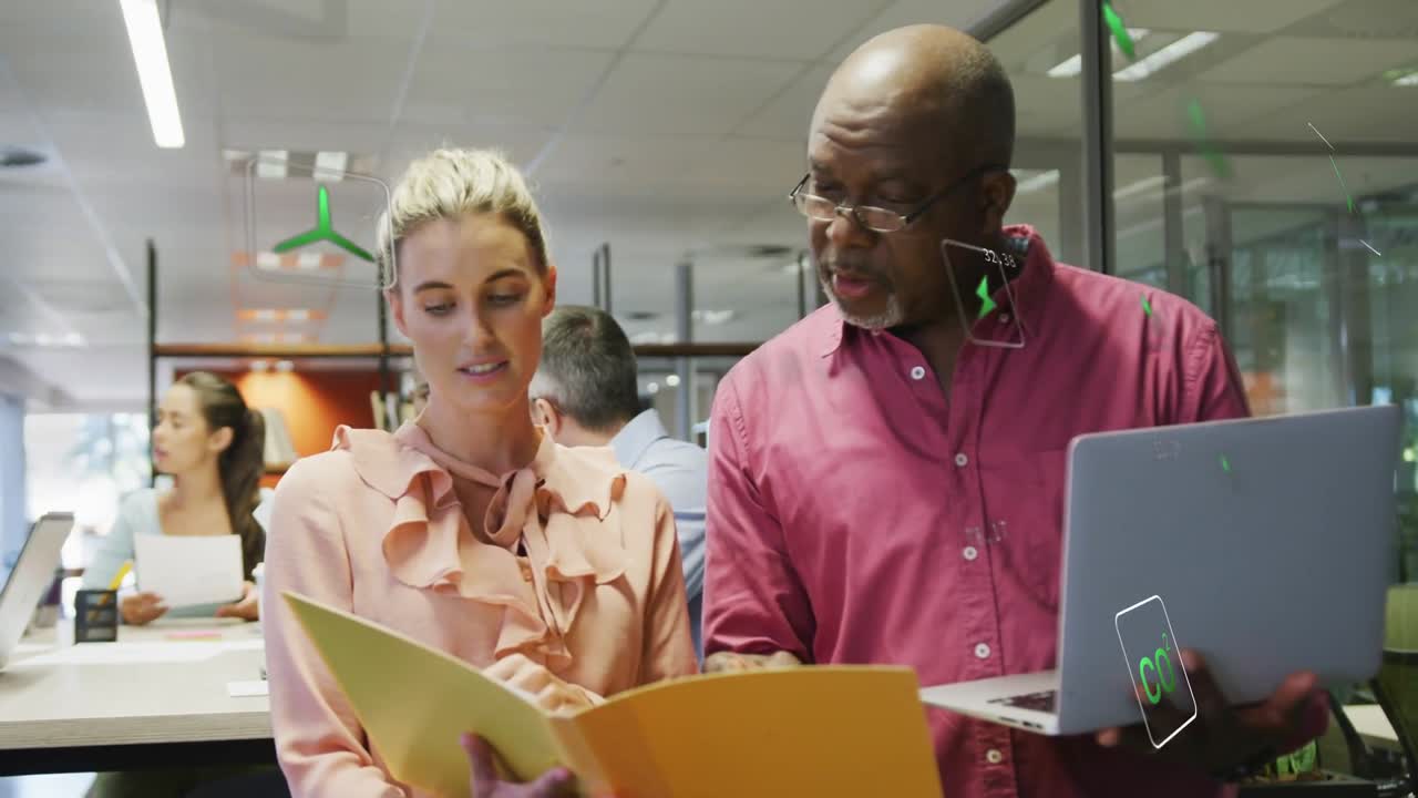 Lead tapping laptop while colleague reviewing folder in business, causing green icons confirming