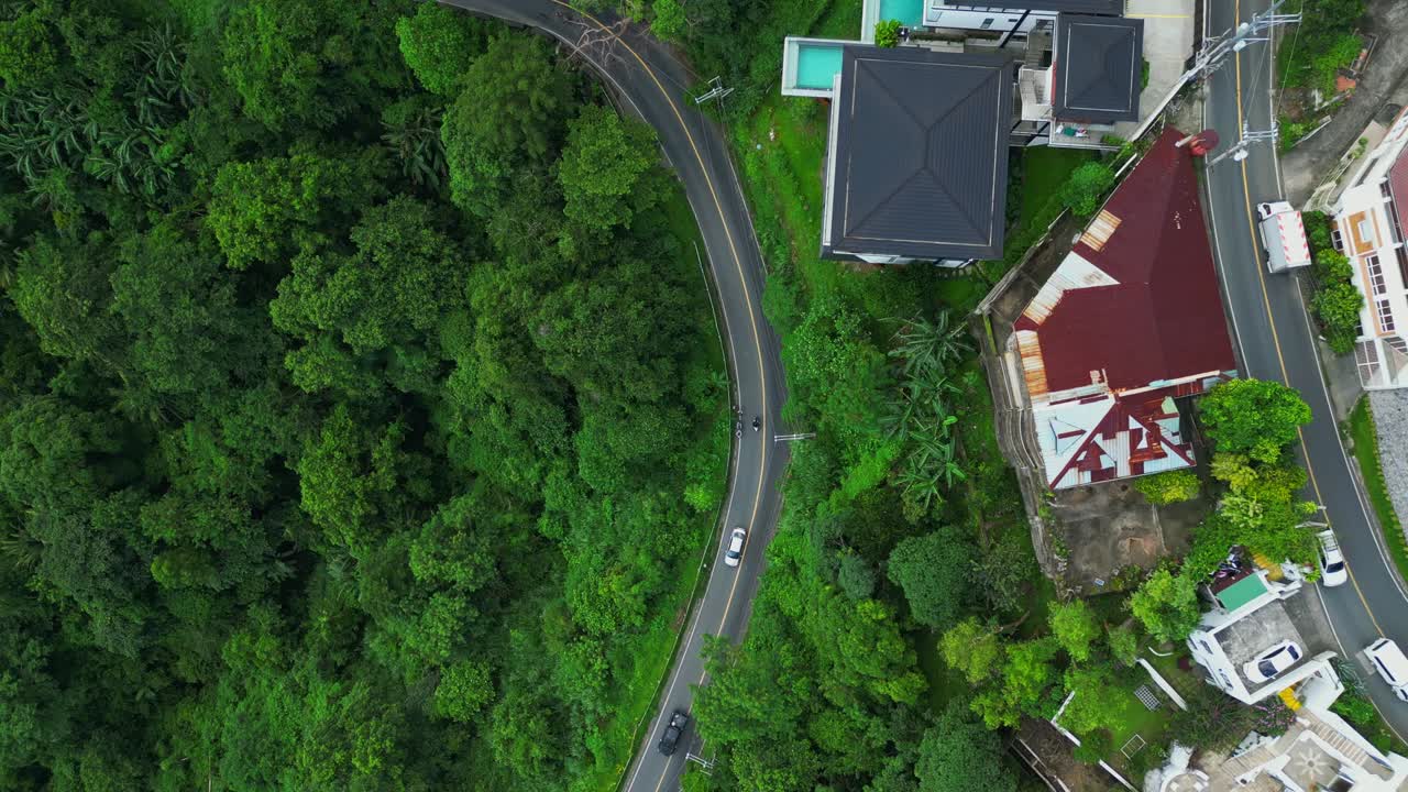 A rotating top-view aerial of Ligaya Drive as a car winds through forested curves in Talisay, Batangas, Philippines
