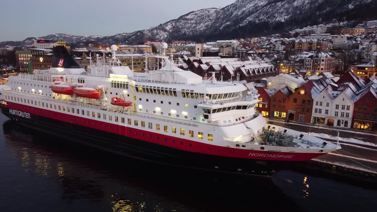 Aerial flying along Hurtigruten Cruise ship NordNorge moored at Bergen Port, Beautiful Bryggen Houses views