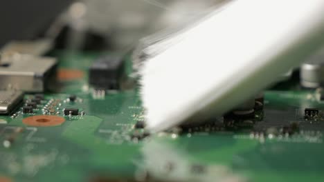 repair of an old laptop, the technician cleans the dirty interior using a brush